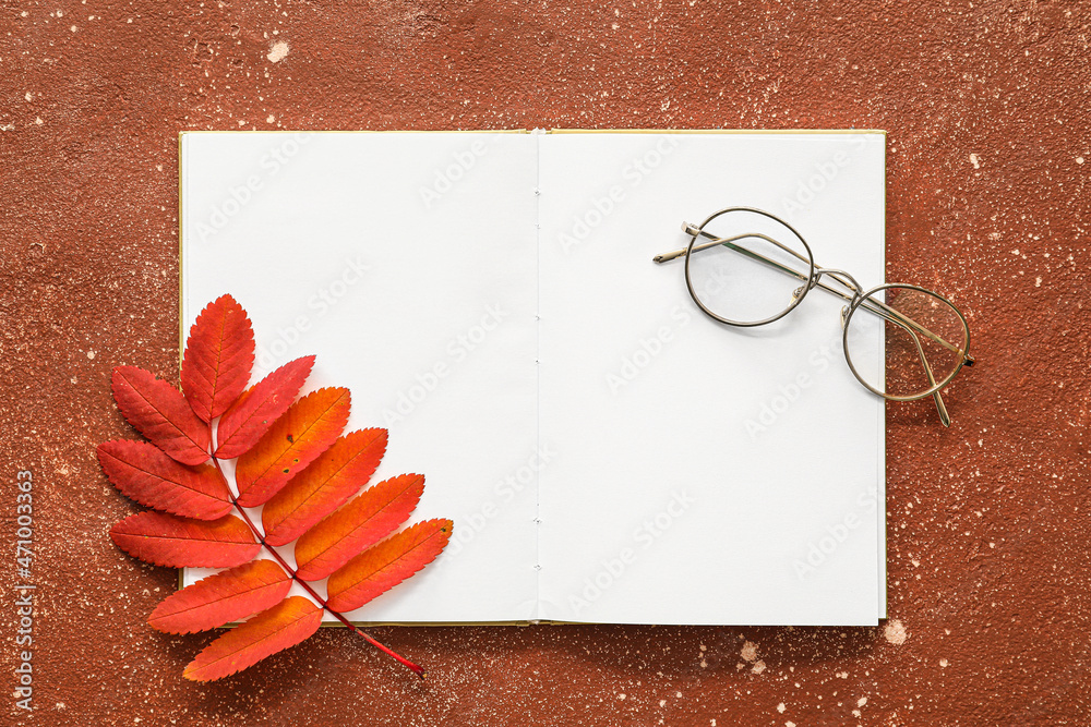 打开的书有空白页、眼镜和彩色背景的秋叶