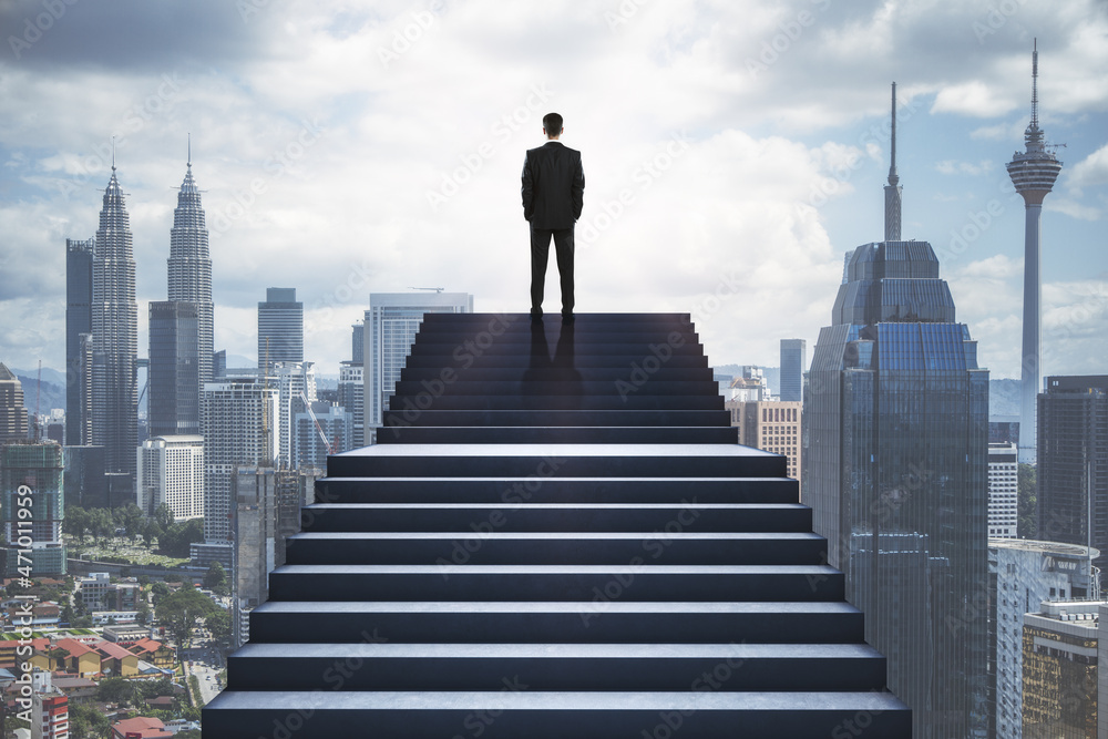 在模糊的城市背景下，一个人站在楼梯上的背影。成功和成长的概念。