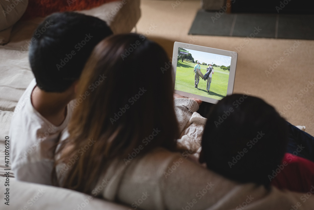 拉丁母亲和孩子在家用笔记本电脑观看高尔夫比赛的背面视图