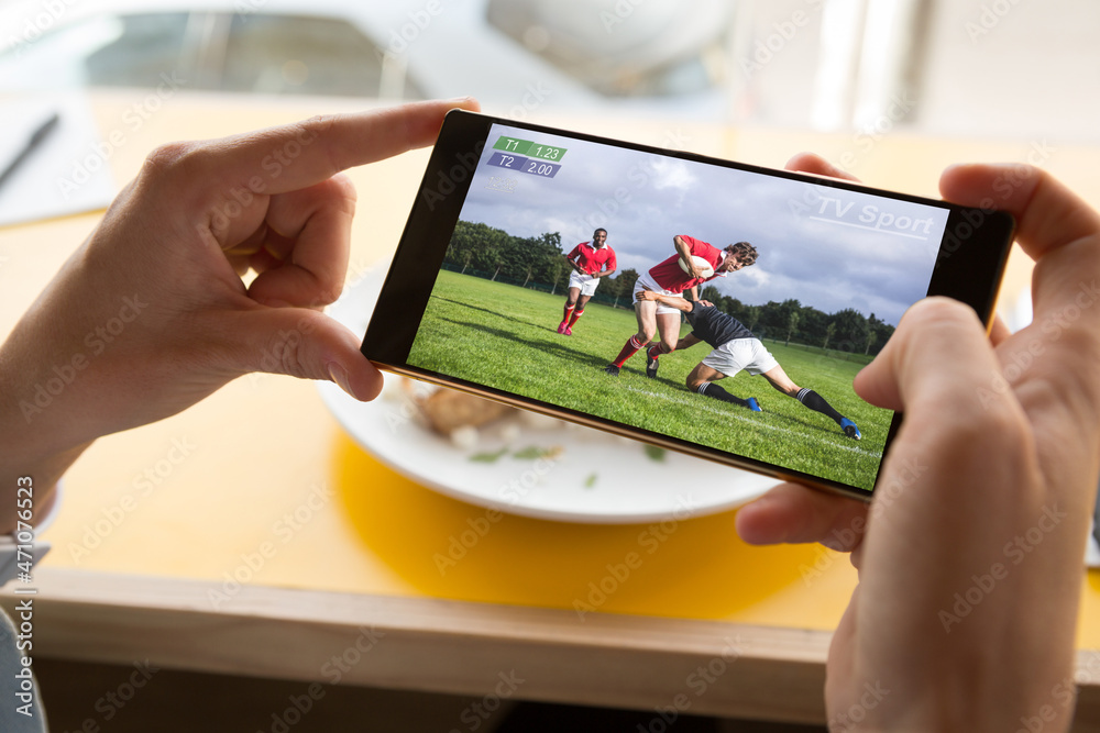 餐厅里用智能手机观看橄榄球比赛的白人男子的手