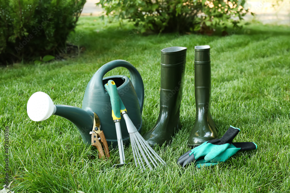 户外绿草上的园艺工具和靴子