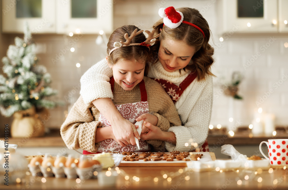 幸福的家庭母亲和女儿在烘焙后装饰圣诞姜饼饼干