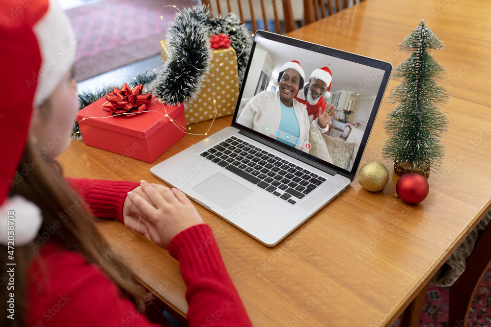 戴圣诞帽的白人妇女与一对非洲裔美国高级夫妇进行笔记本电脑圣诞视频通话