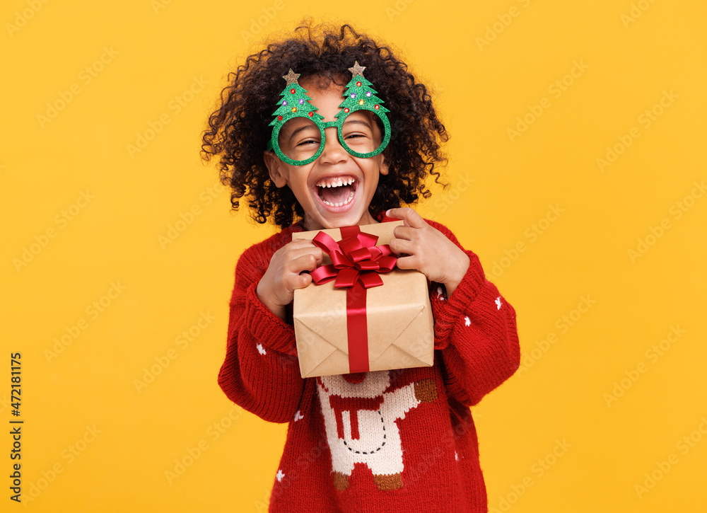 快乐的美国黑人小男孩戴着圣诞树形状的滑稽眼镜，带着圣诞礼物