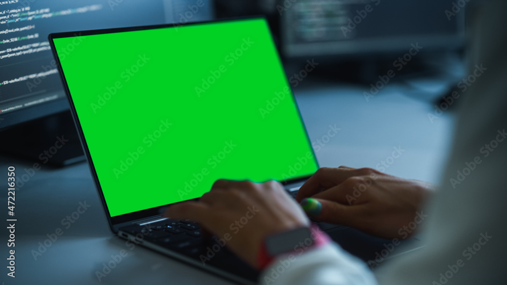近距离关注在绿屏Chroma键笔记本电脑键盘上打字的人