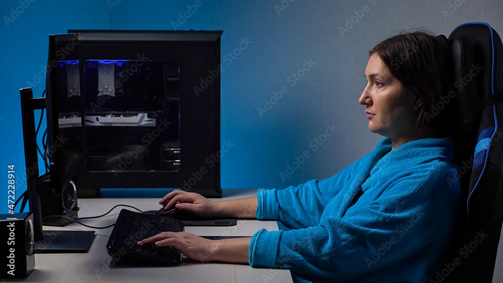 年轻的黑发女性长期雇佣，坐在电脑屏幕上紧张地玩游戏。