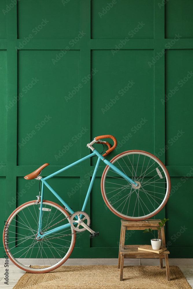 现代自行车、带书的阶梯和靠近绿色墙壁的花盆