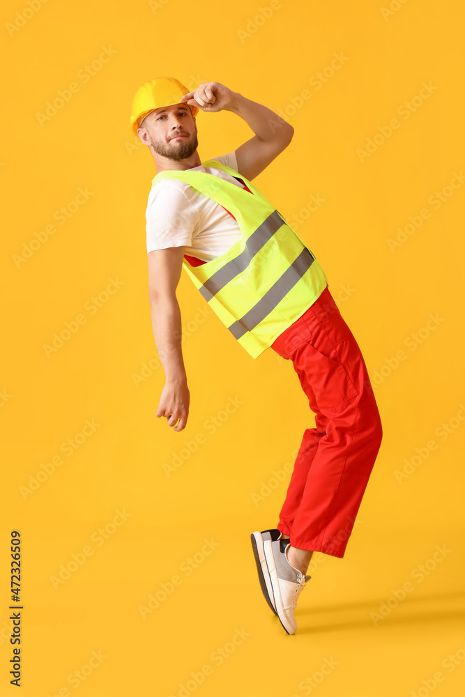 在黄色背景上跳舞的年轻男性工人