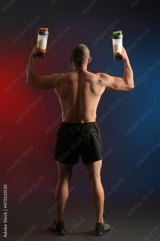 男性健美运动员，深色背景下有蛋白奶昔，后视图