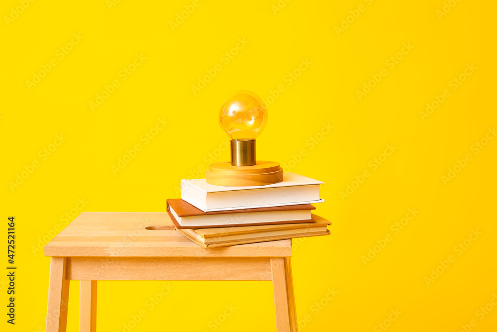 黄色背景上有书和灯的木制台阶凳