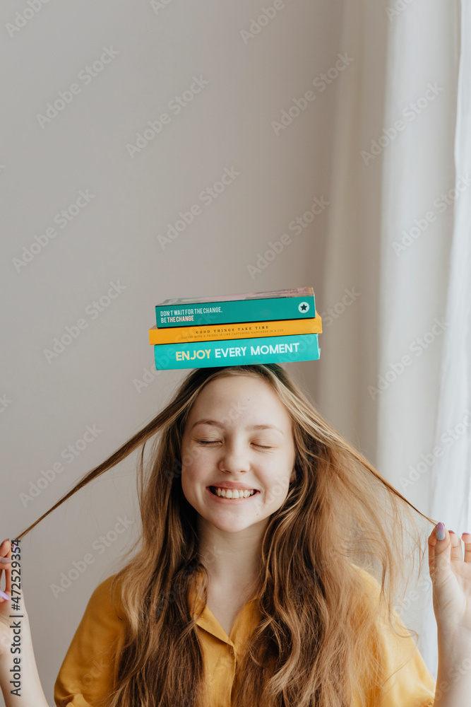 快乐的金发女孩在头上平衡书本