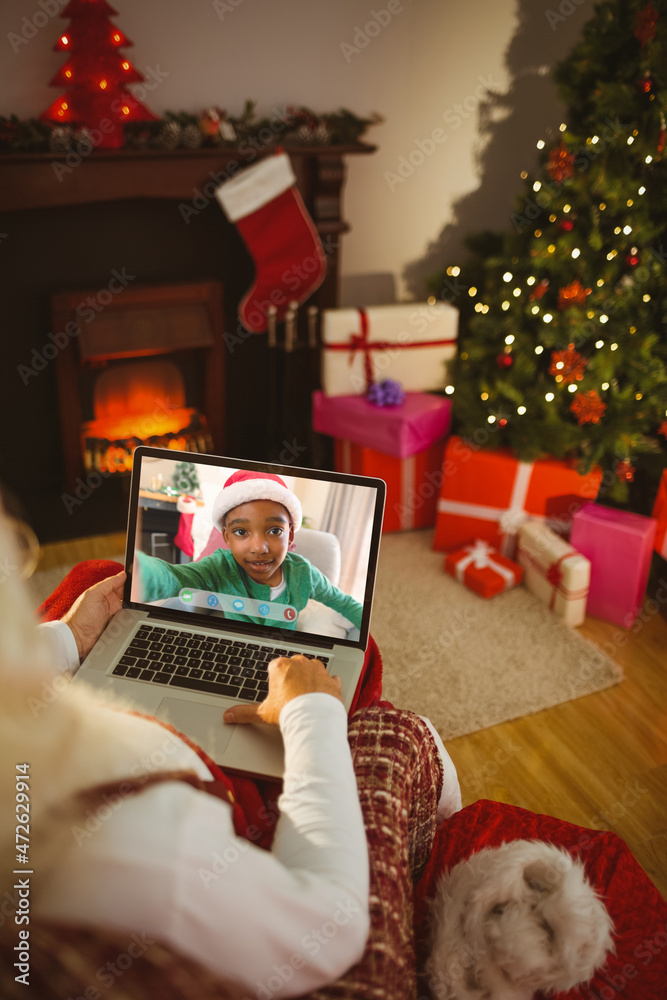 圣诞老人与微笑的非裔美国男孩进行笔记本电脑圣诞视频通话