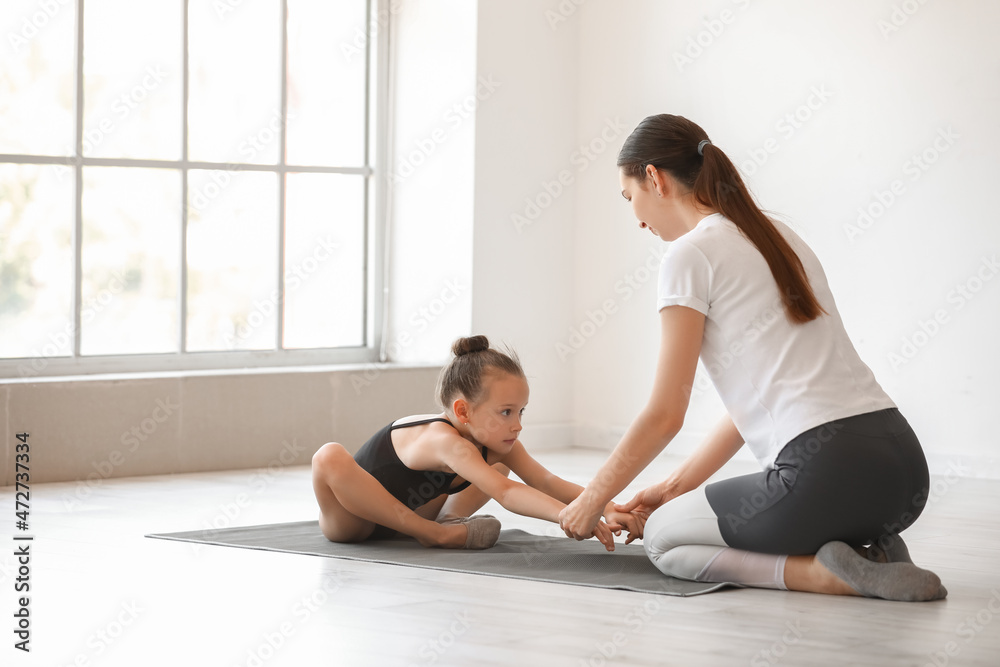 教练帮助小女孩在健身房做体操