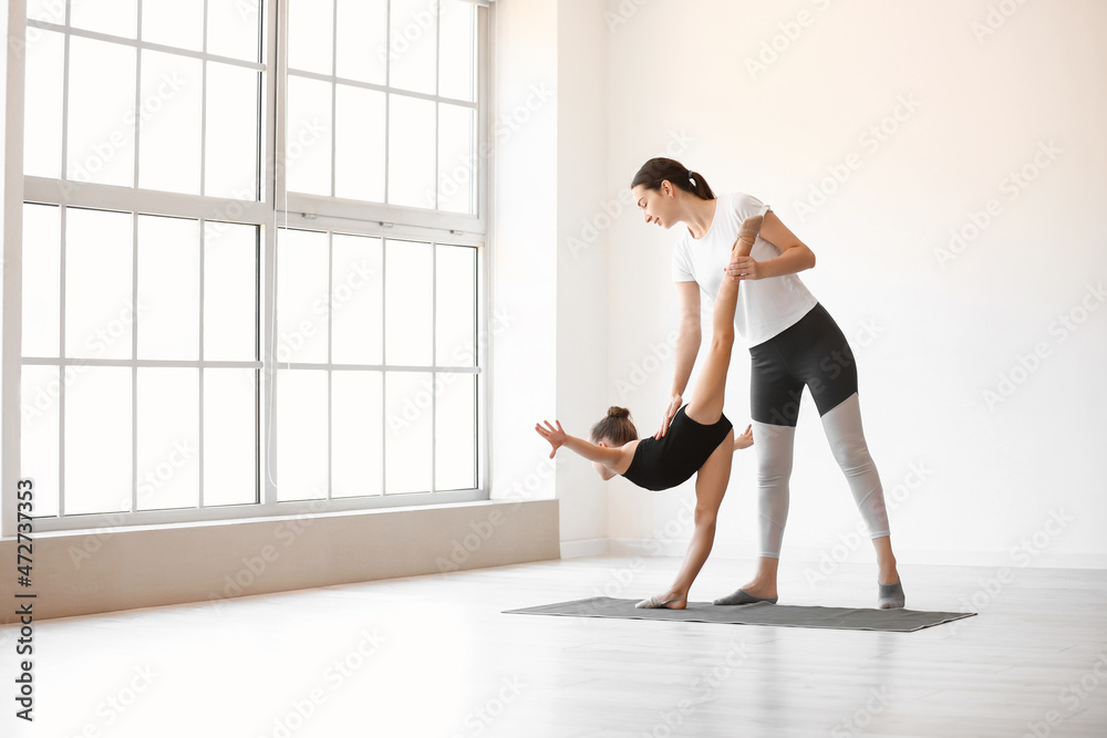 教练在健身房帮助小女孩做体操