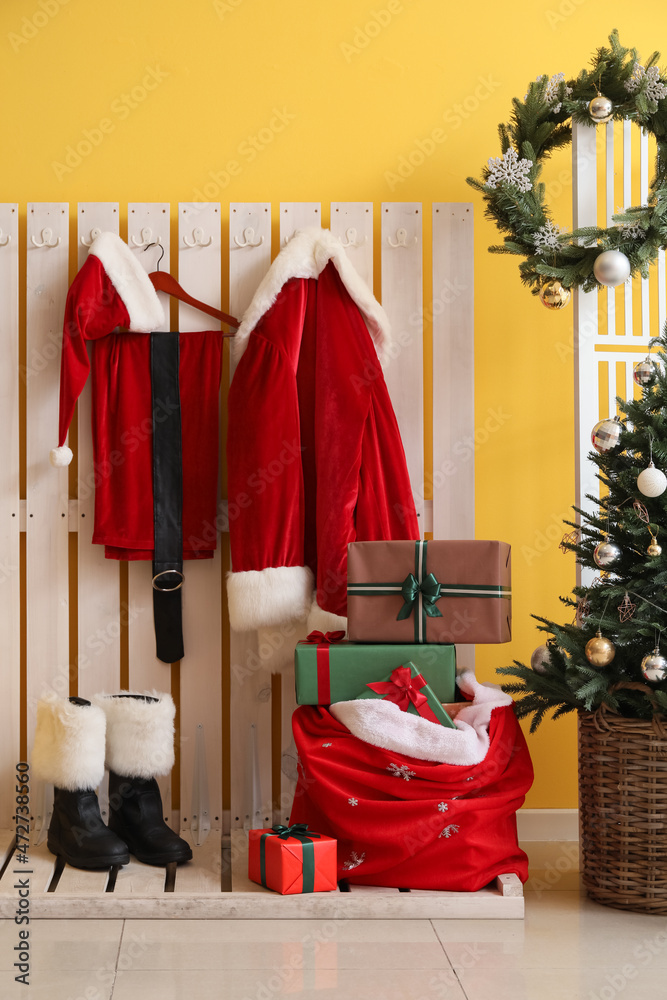 走廊彩色墙附近挂着圣诞老人服装、靴子和礼品盒的衣架