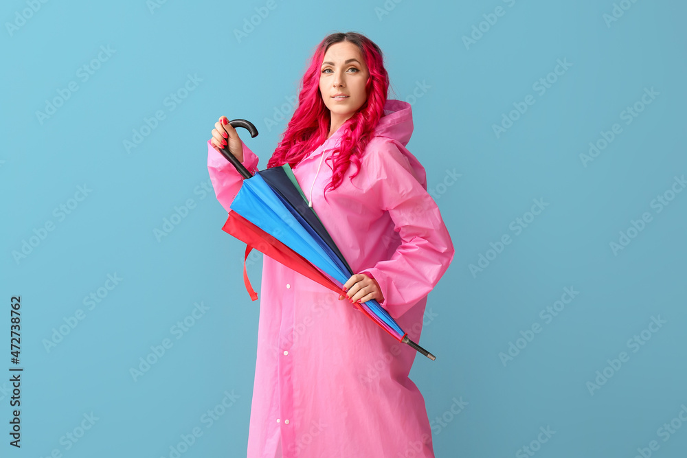 美丽的女人穿着雨衣，颜色背景上带着雨伞