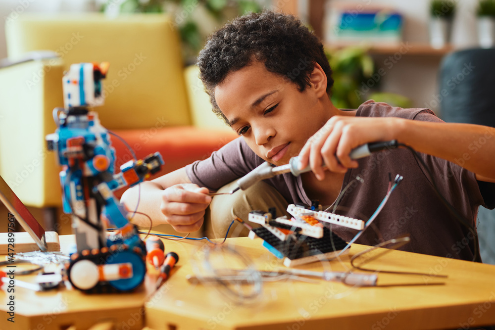 聪明的非洲男孩在家里为科学课制作机器人。机器人与教育。