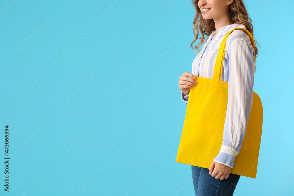 漂亮的年轻女人，蓝色背景上有黄色环保袋