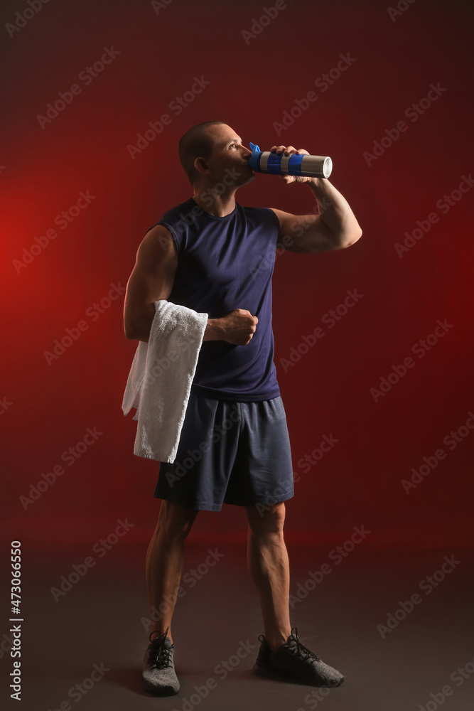 男性健美运动员在深色背景下饮用蛋白奶昔