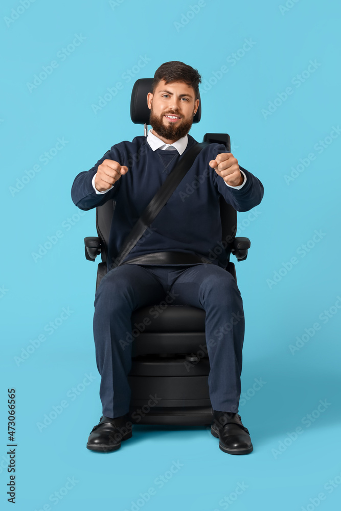 蓝底汽车座椅上有假想方向盘的英俊男子