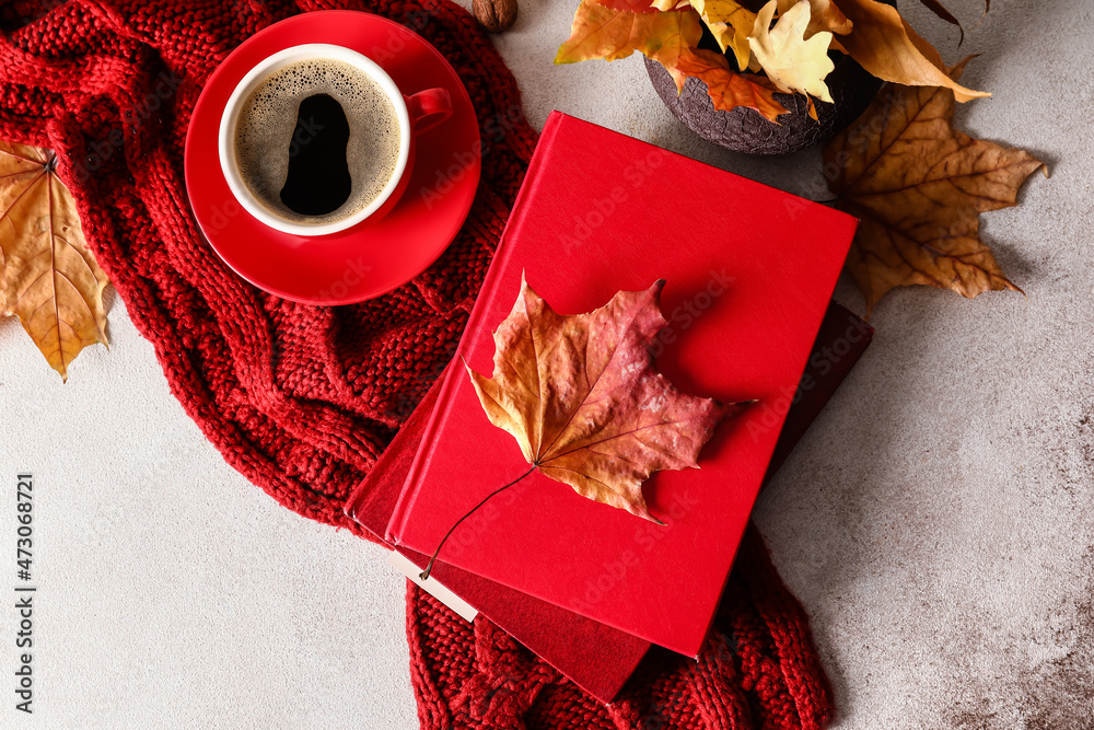 一摞书、针织围巾、一杯咖啡和浅背景秋叶花瓶
