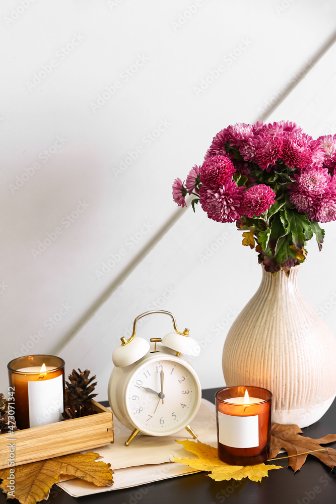 在烛台上燃烧蜡烛，桌子上放着美丽的菊花和秋叶的花瓶nea
