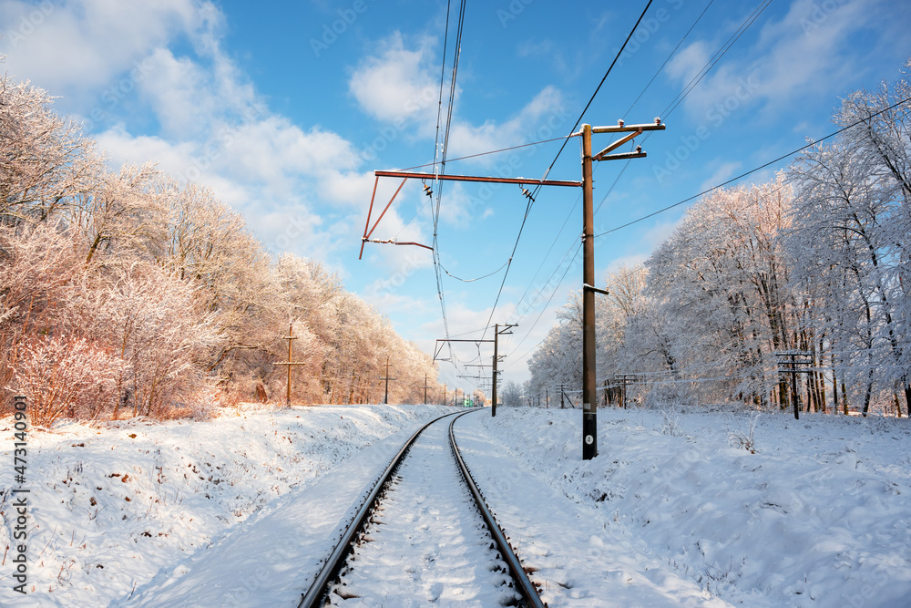 冬季森林中有电气干线的空铁路。日落时有铁路的雪景