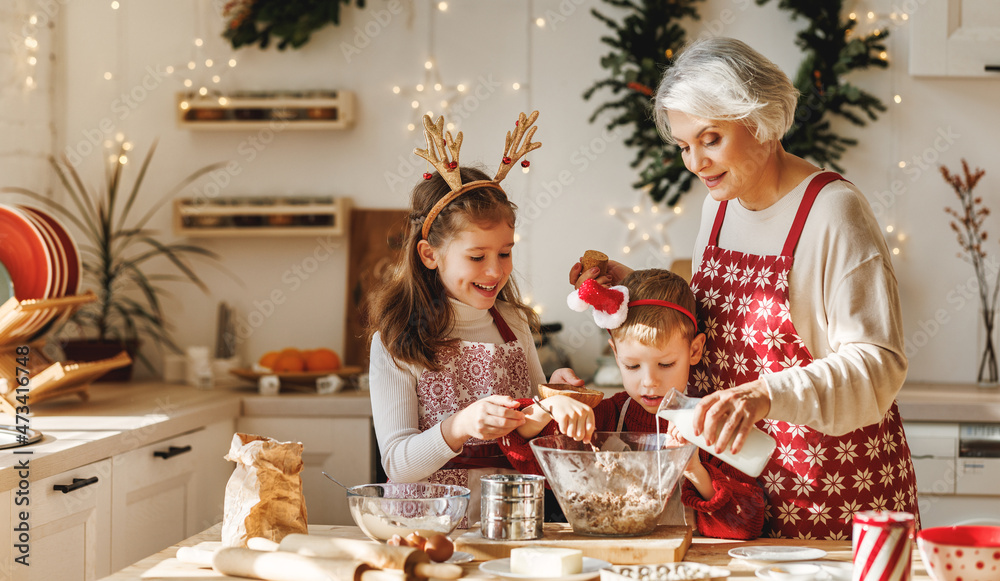 两个小孩和年迈的祖母一起在厨房做圣诞自制饼干