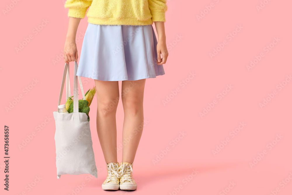 年轻女子拿着环保袋，粉红色背景是食物和饮料