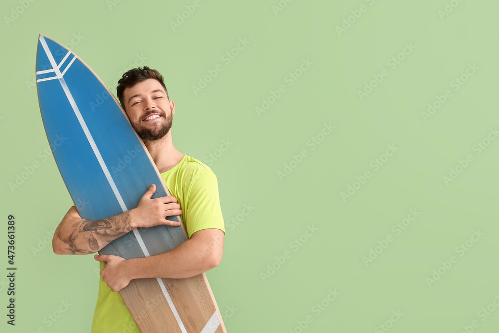 绿色背景下英俊的大胡子男子拥抱冲浪板