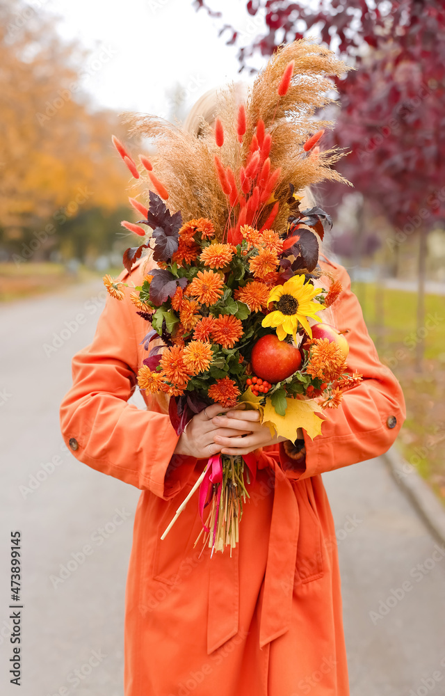年轻时尚女性在秋季公园手捧花束