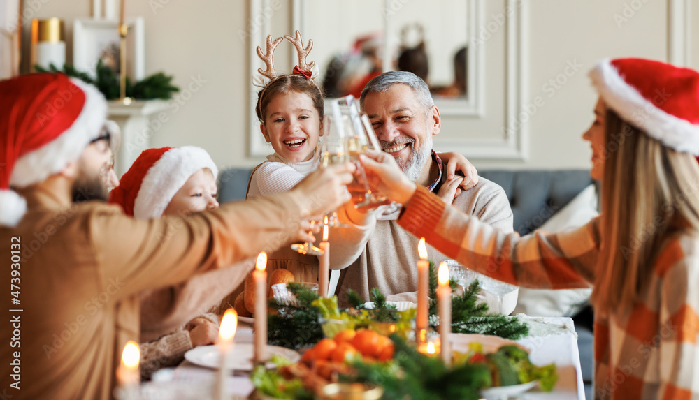 幸福的多代大家庭在圣诞节庆祝期间享受圣诞大餐，碰杯