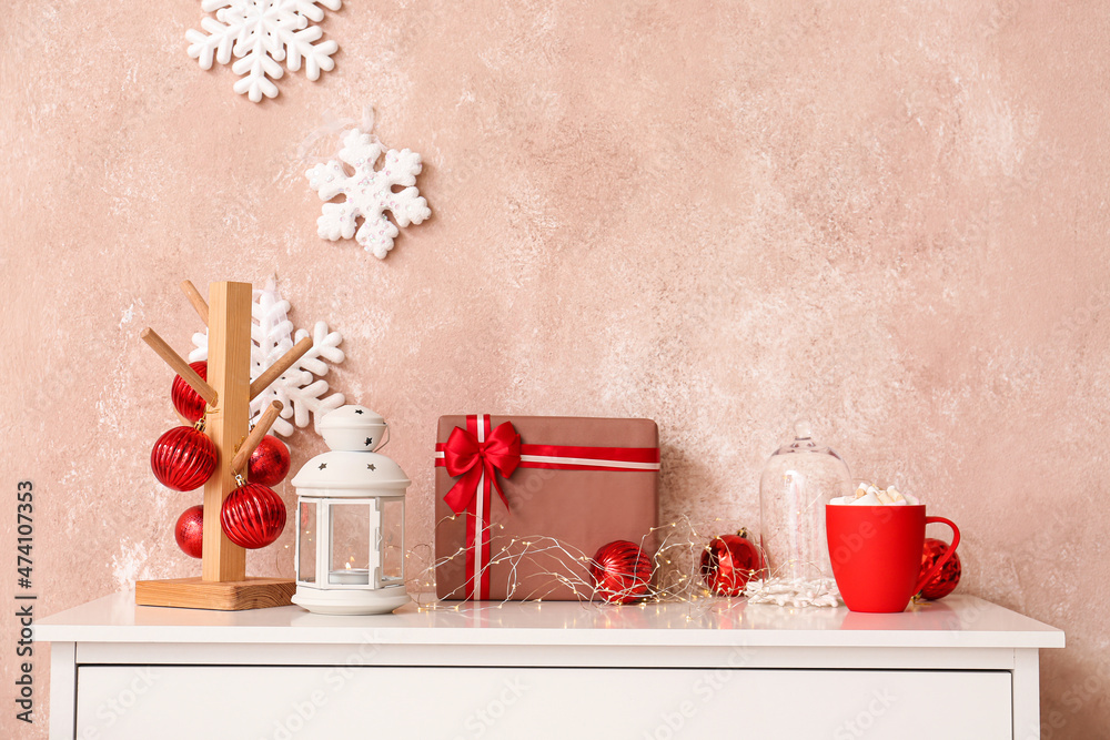 彩色墙附近桌子上的圣诞礼物、灯笼和装饰