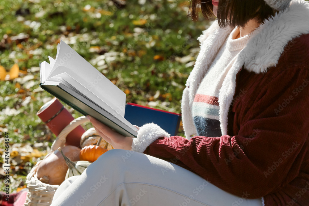 阳光明媚的秋天公园里的女人在看书
