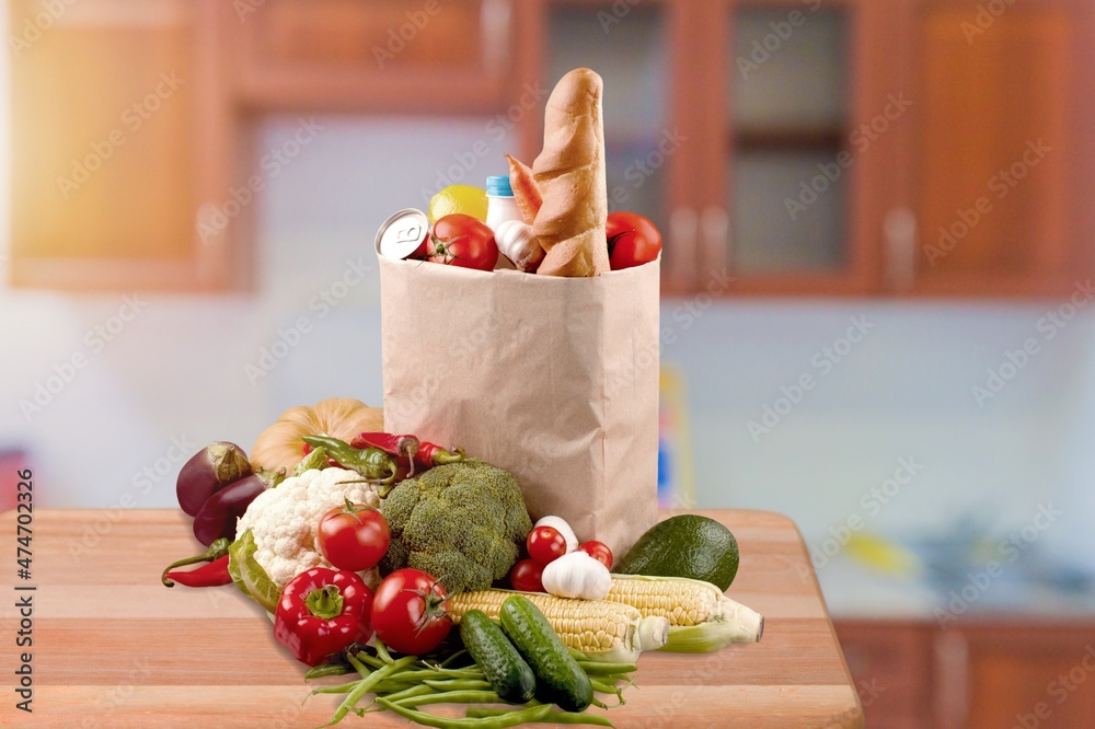 Various fresh vegetables in paper grocery bags on kitchen