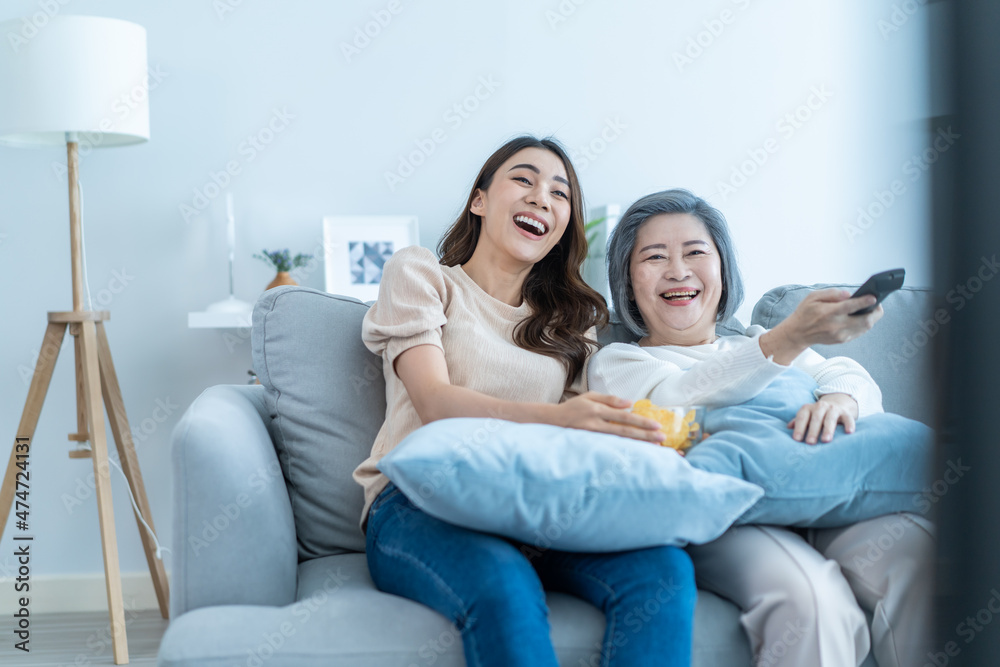 亚洲高级熟女和女儿坐在沙发上看搞笑电影。