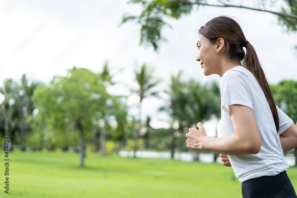 亚洲年轻美丽的运动女性在公园的街道上奔跑。