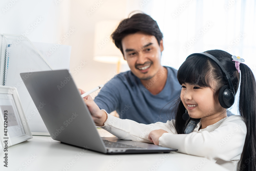 亚洲小女孩在家和父亲一起学习网课。