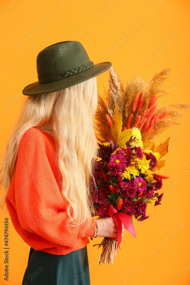 戴帽子的女人在彩色背景上拿着美丽的秋季花束