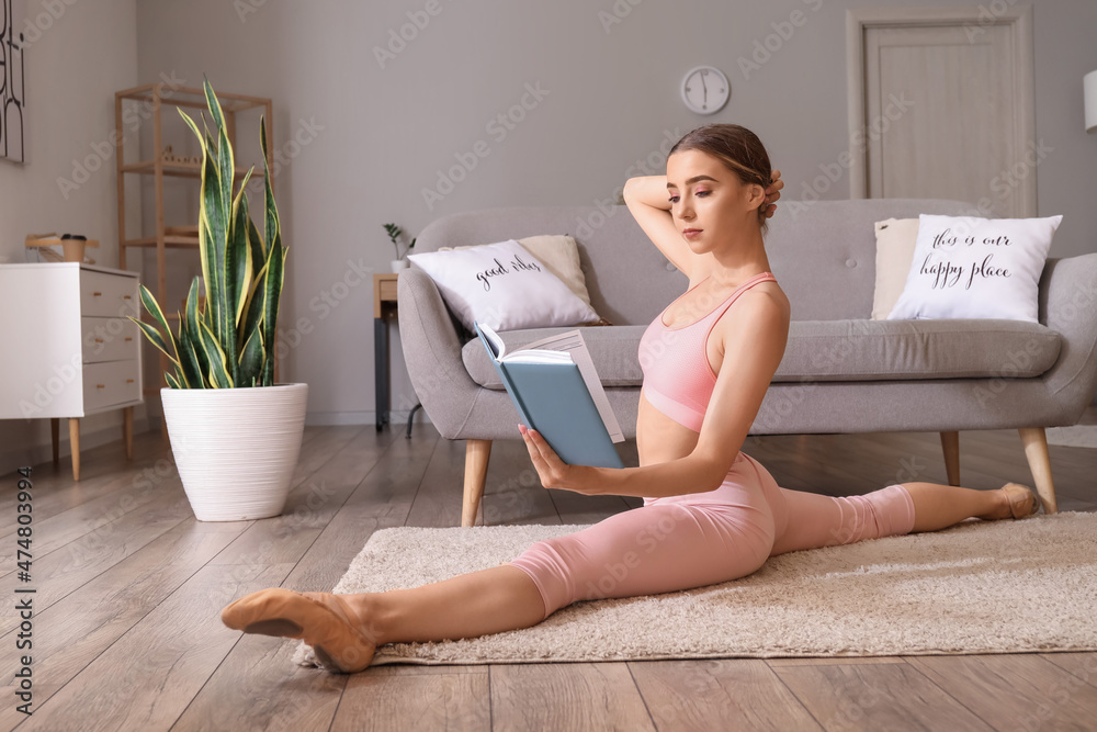 美丽的年轻女子在家做劈腿时看书