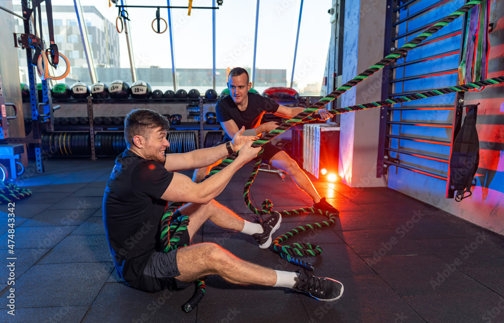 现代健身房里的运动健将。两个活跃的男人在健身房锻炼。