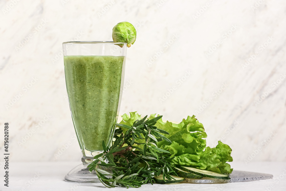 一杯健康的绿色奶昔和淡背景蔬菜