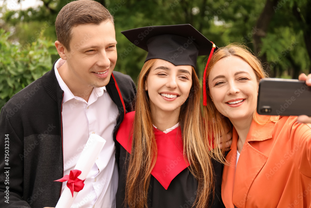 快乐的年轻女子和她的父母在毕业那天自拍