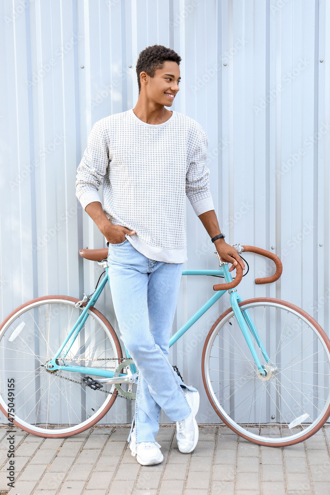 非洲裔美国少年骑自行车靠近蓝色围栏