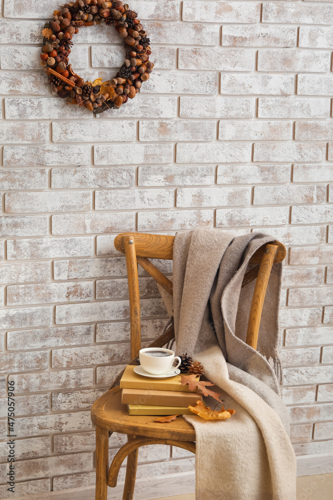 浅色砖墙上挂着漂亮的橡子花环，房间椅子上放着一杯咖啡和书