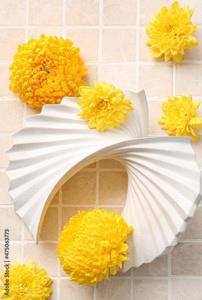 美丽的陶瓷装饰和淡背景上的黄色菊花