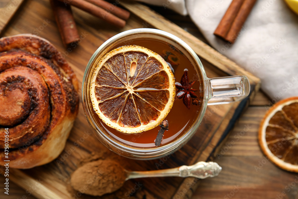 一杯美味的橙色茶，木质背景上有肉桂，特写