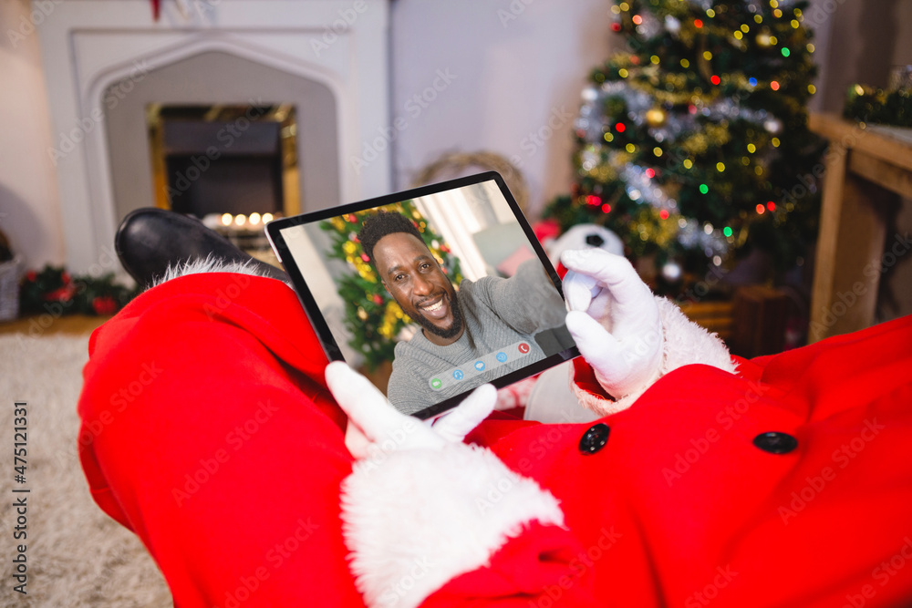 Santa claus making tablet christmas video call with smiling african american man