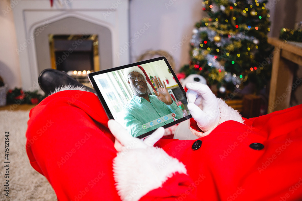 圣诞老人与戴圣诞老人帽微笑的非洲裔老人进行平板电脑圣诞视频通话