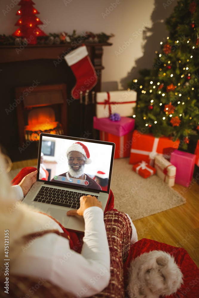 Santa claus making laptop christmas video call with smiling senior african american man in santa hat